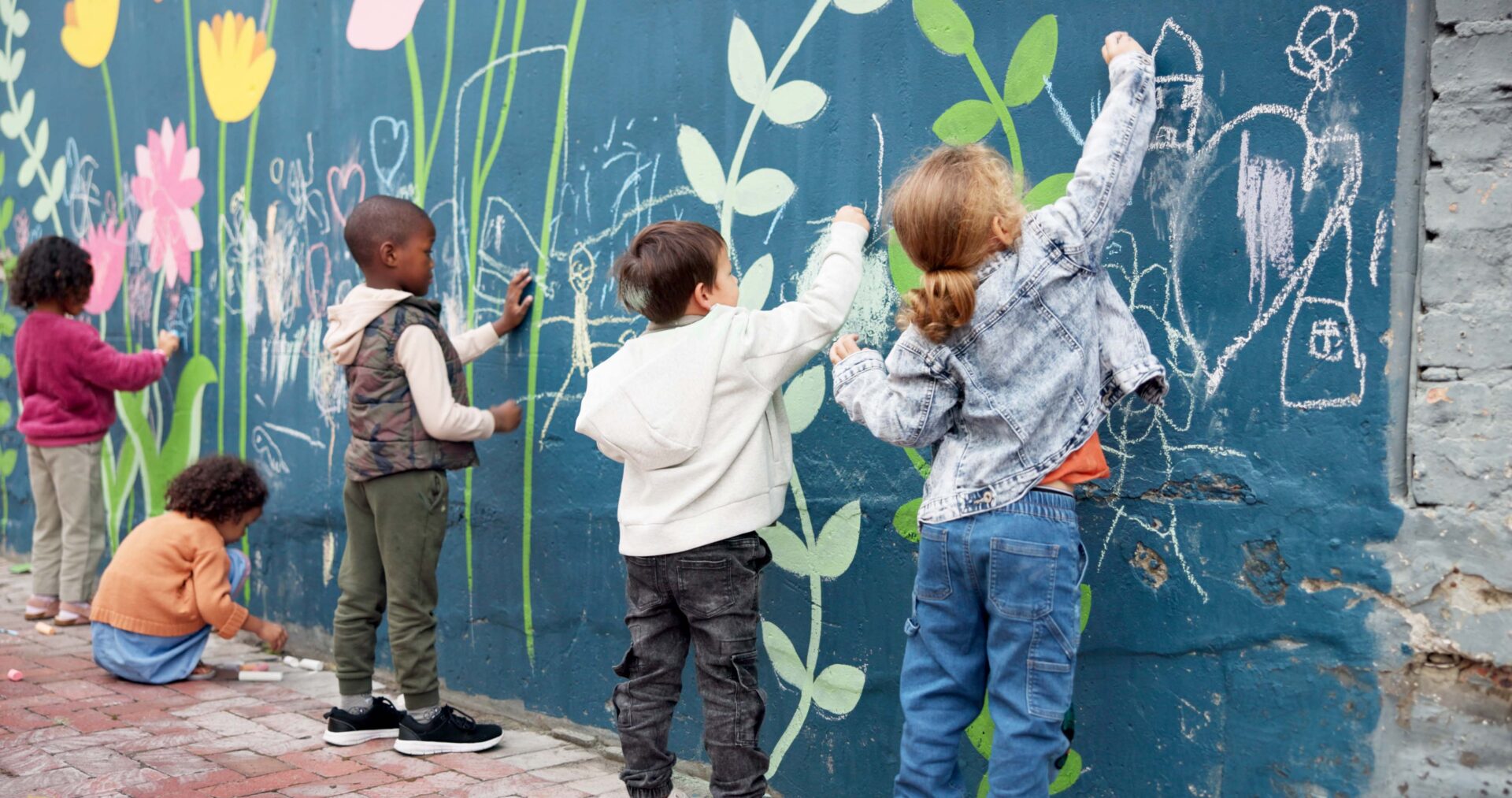 Kinder bemalen eine blaue Wand mit Blumen
